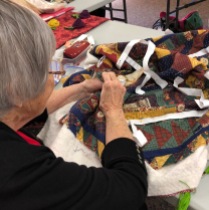 Helen working on hand stitching a quilt